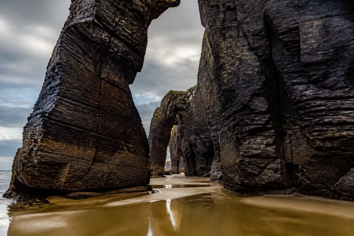 Arches de roche sculptées par la mer sur une plage atlantique à marée basse